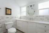 The remodeled bathroom features a marble backsplash and penny-tiled floor.