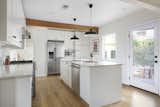 An original wooden beam spans across the width of the kitchen, a room which was treated to a complete overhaul as part of the remodel. Now, stainless steel appliances mingle with custom cabinetry while a central island provides ample space for meal prep.  Photo 10 of 15 in 15 Modern Kitchen Island Ideas from A Spanish-Style Charmer With a Backyard Studio Slides Onto the L.A. Market at $1.4M