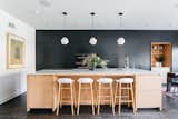 Custom black cabinetry spans the back wall in the kitchen, adding a dramatic punch of color against the geometric, white pendants hanging over the large, central island.