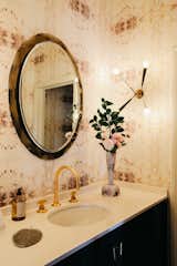 The chic half-bath on the main level is fitted with patterned wallpaper and gold accents.