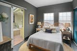The main bedroom features dark-gray walls and warm-toned furniture and art.