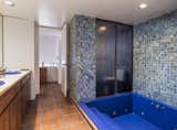 The principal bathroom boasts colorful artisan tiles and a bright-blue vintage tub.
