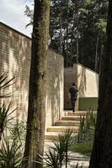 The home’s imposing entrance conceals a tranquil inner courtyard.  Photo 2 of 19 in A Curvaceous Brick Home Follows the Edge of a Forest Near Mexico City