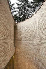 The exterior wall’s gentle curve conveys a sense of enclosure.  Photo 4 of 19 in A Curvaceous Brick Home Follows the Edge of a Forest Near Mexico City