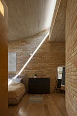 Afternoon sunshine casts a graphic beam on the wall of the master bedroom.  Photo 11 of 19 in A Curvaceous Brick Home Follows the Edge of a Forest Near Mexico City