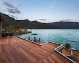 The owners replaced the original decking material, which was pressure-treated pine, with a clear redwood grade, allowing the deep, reddish hues to contrast with the sparkling blue water steps away.  Photo 4 of 10 in A Three-Level Redwood Deck Spurs a Spellbinding Link to Nature Near Cascade Bay