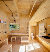 Large windows bring ample natural light inside the 130-square-foot structure. While the toilet is positioned inside the cabin, the shower is located on the exterior and is hidden from view.&nbsp;