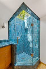 The en suite bath features an oversized blue-tiled shower, capped with a large skylight.