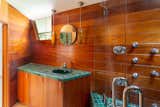 Emerald-green tile continues into the wood-clad bath, which features a large glass shower.
