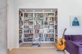 A small, carved-out library nook is fitted with walls of floor-to-ceiling shelving.