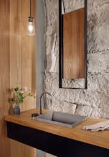Bath Room, Drop In Sink, Pendant Lighting, Wood Counter, and Stone Slab Wall  Photos from A Private Wine Cave Is Built Into a Limestone Hillside in Texas
