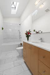 Marble tiles extend across the shower wall and floors in the upper-level bathroom.