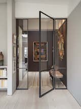 An elegant steel-framed glass door sweeps out from a dramatic entryway.