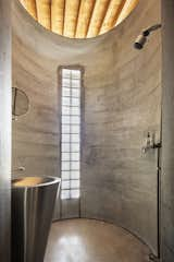 Bath Room, Open Shower, Pedestal Sink, and Concrete Floor Adjacent to the soaring family room is an impressive, although curiously placed, concrete silo shower embedded with glass bricks.  Photos from An 11-Year Renovation Helps a Couple Grow Simpatico With the Original Homeowner’s Quirky Vision