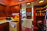 The small yet functional kitchen is located off the main living room and boasts original cabinetry. Red-tinted concrete tiles line the floor.