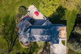 An aerial view of the property shows the home’s rectangular core and the lush surrounding lot.