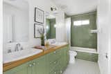 The green-hued bathroom features a double-sink vanity and a large soaking tub.