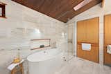 The primary suite includes a spa-like bath complete with travertine walls, heated floors, and an oversize tub.