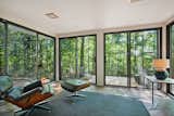 &nbsp;Sliding glass doors wrap around the rear sunroom, opening the space to the wooded lot.