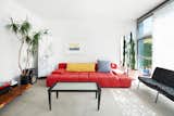 In the living room, a bright red sofa pops against the surrounding white walls.