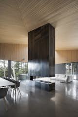 Living Room, Sectional, Chair, Table, Concrete Floor, and Two-Sided Fireplace  Search “trennza-side-chair.html” from A Cathedral-Esque Lake Home Rises in the Quebec Countryside
