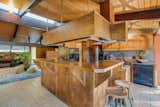 The open kitchen features a custom, L-shaped wooden island with bar stools.