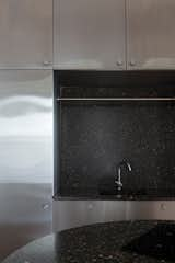 The kitchen pairs dark terrazzo with stainless steel.