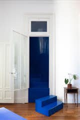 A new stair wrapped in a metal cocoon and painted with bright blue leads up to the attic which the couple converted into the primary bedroom.