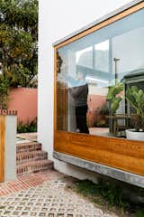 On the east side of the home, two large bay windows, their wood frames sandwiched between concrete, have hinged side panels that open to let in breezes. “The bay windows are like two eyes,” says Derek. “My favorite aspect of the house is at night when the lights are on, and they  act like weird two-way mirrors. You can see it’s night outside, but they reflect the interior in a way that gives it a sense of being a completely different space.”