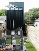 The exterior is clad in black standing-seam metal siding, while a terrace with a family-size sectional sits on the roof. Even on a small lot, there’s room for a backyard with a trampoline.