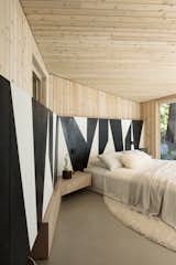 Bedroom, Bed, Rug Floor, Concrete Floor, Night Stands, and Lamps  Photo 12 of 20 in An Angular Black Cabin Rises From the Woods Near Vancouver