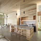 Kitchen, Granite Counter, Range Hood, Pendant Lighting, Track Lighting, Concrete Floor, Range, and Metal Cabinet  Photo 6 of 20 in An Angular Black Cabin Rises From the Woods Near Vancouver