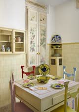 In the kitchen, a set of painted wooden chairs around the table include geometric details.