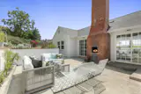 An expansive backyard patio located right off the living room and kitchen features plush seating, an outdoor fireplace, and a terraced garden.