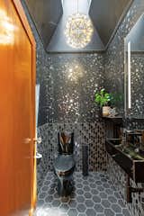 One of the home's half-bath—referred to as the "Galaxy Powder Room"—is dressed in wallpaper from Graham &amp; Brown and boasts Heath tile on both the floor and walls.