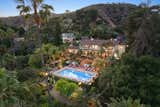 An aerial view of the property showcasing its lush setting and wide backyard terrace—an idyllic hub for lounging, dining, and entertaining. The structure behind the main residence is the three-bedroom guest house.