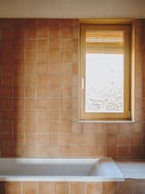 The bathroom is clad in terra-cotta tile, echoing the kitchen.