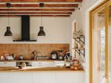 Terra-cotta tiles clad the kitchen backsplash, and the countertops are made of oak.