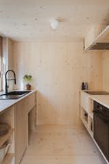 Kitchen, Wood Counter, Cooktops, Drop In Sink, Wall Oven, Ceiling Lighting, Light Hardwood Floor, Wood Cabinet, and Wood Backsplashe  Photos from This Spruce Cabin in Switzerland Is Like a Grown-Up Tree House