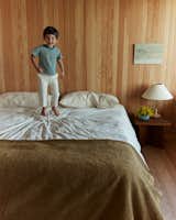 The couple's son, Felix, jumps on their bed in the bedroom upstairs.