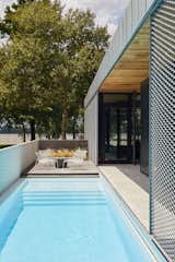 A weathered black locust deck merges with a 40-foot lap pool that doubles as a heat sink for the home’s geothermal system. The Hot Mesh lounge chairs are from Blu Dot.