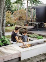 In the backyard, a fire pit also serves as a grill thanks to grates that slide back and forth on steel rails. “We cook on it all the time,” says Briana. “I think it’s my husband’s favorite part of the house.”  The fire pit was designed by Briana and features and grates from Grate Grates. The patio chairs shown in the background are from Direct Furniture Modern Home.