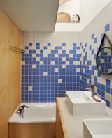 While the rest of the home carries a neutral tone, the single bathroom shouts by comparison, with blue and off-white stoneware tiles arranged in a pixelated gradient. The Contesa bathtub is from Cedeo, the sinks from Roca, and the faucets from Grohe.