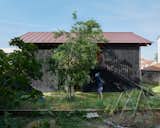 In the backyard, a 1,056-gallon cistern stores rainwater for flushing toilets and watering plants—including a vegetable garden and plum, cherry, and fig trees. The home’s red zinc roof takes its color cue from neighboring buildings.  Photo 11 of 15 in An Eccentric Facade Turns Heads at This House Outside Paris
