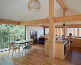 A large sliding glass door treats the kitchen and dining area to views of the surrounding foliage—including a plum tree that yields fruit for Blandine’s pies. In warm weather, she pulls her dining table onto the balcony to create an alfresco office. A globular Octo pendant by Secto Design can light the area from above. The dining chairs are from Caravane, and the artwork is by Philippe Charles.  Photo 4 of 15 in An Eccentric Facade Turns Heads at This House Outside Paris