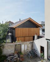 Outside Paris, Blandine Minot and Olivier Stora’s home appears to float above a preexisting wall. The second story is wrapped with louvers, which shade the interior and provide privacy. “We were interested in the idea of a structure secretly staring at the street,” says architect Sihem Lamine of Arba. The roof panels are from VMZinc.  Photo 1 of 15 in An Eccentric Facade Turns Heads at This House Outside Paris