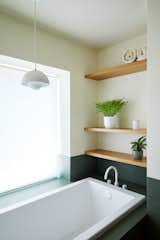 Downstairs, the color returns in the primary bathroom, where the designers took out carpeting and a glossy black toilet and put in a Zuma tub beneath an &amp;Tradition Flowerpot pendant.