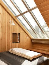 In an upstairs bedroom, glass panels offer views of the sky. The sconce is from Schoolhouse Electric, and the blanket is from Pendleton.