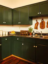 Bronte painted the kitchen cabinets a deep green and added white hardware for contrast. The teak cutting boards are from Goodies LA.