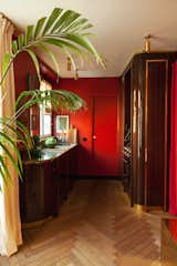 Kitchen The kitchen features red-painted walls, lacquered wood floors, and rounded cabinetry made from Macassar ebony with brass edges and Rain Forest stone countertops.  Photo 1 of 7 in A Designer’s Small but Sumptuous Apartment Lists for €410K in Paris